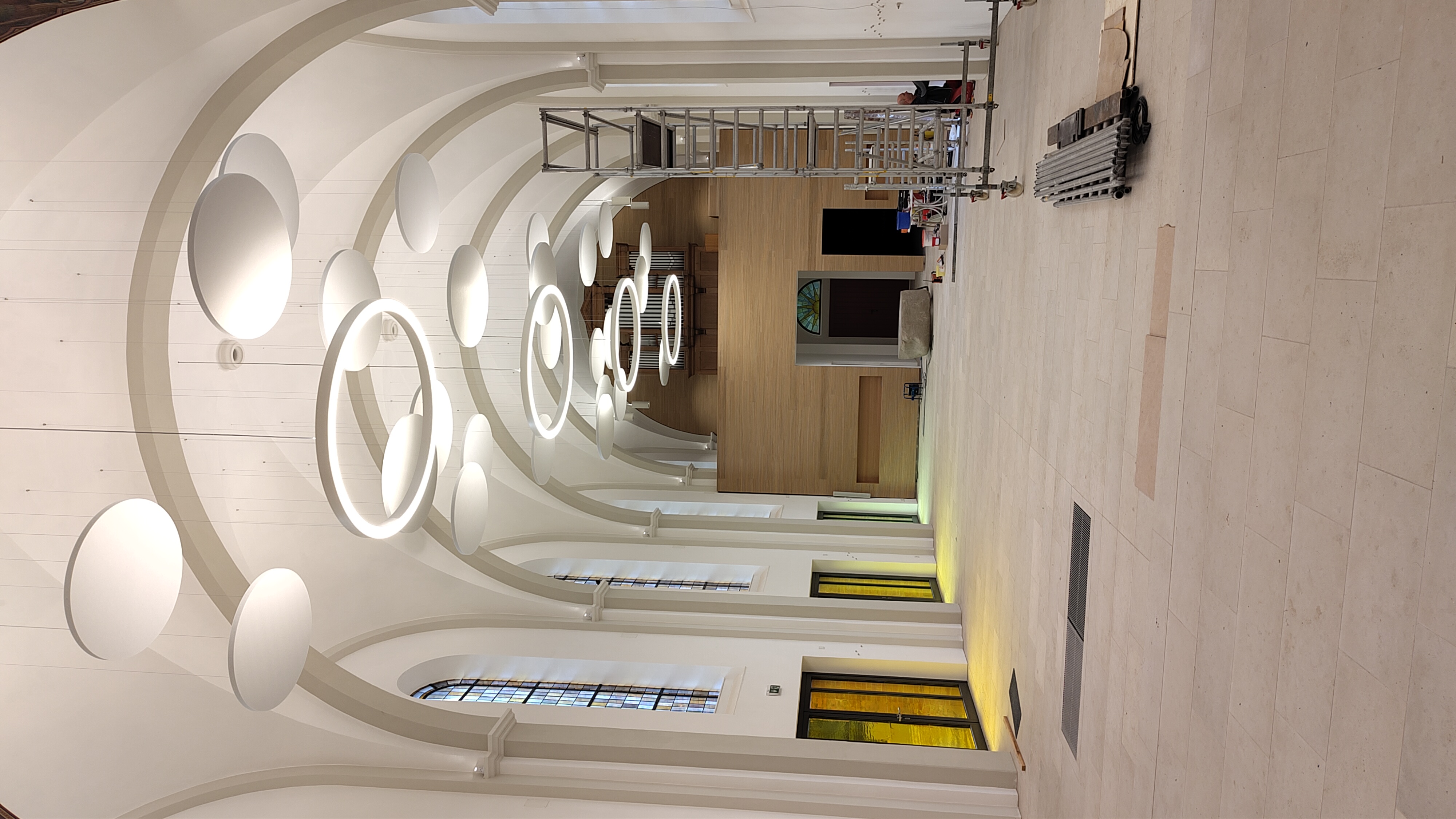 Leerer Kirchenraum mit Akustikbaffeln an der Decke und Bauleiter an der Wand
