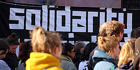 Banner solidarity mit Menschen davor