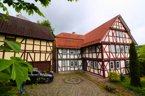 Fachwerkhaus mit rotem Dach und Scheune nebendran