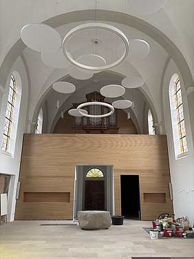 Innenansicht Kirche mit runden Deckenlampen und Akustikbaffeln