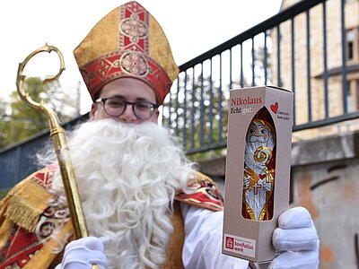 Als Bischof Nikolaus verkleideter Mann geht durch die Straßen mit Schokoladennikolaus in der Hand