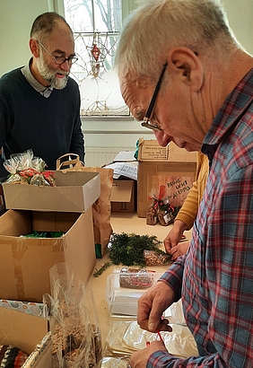 Zwei Herren packen kleine Tüten ein
