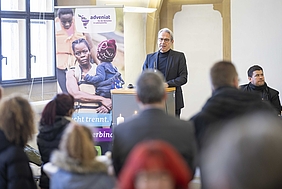 Redner am Pult vor Zuhörern