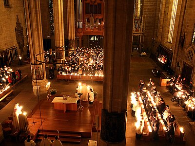 Versammelte Gottesdienstgemeinde im Erfurter Dom bei Nacht mit brennenden Kerzen in der Hand