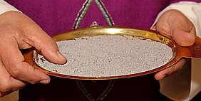 Zwei Hände, die eine Schale mit Asche halten