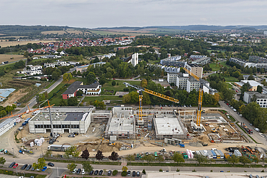 Schulgebäude im Bau mit Kran und Gerüst von oben