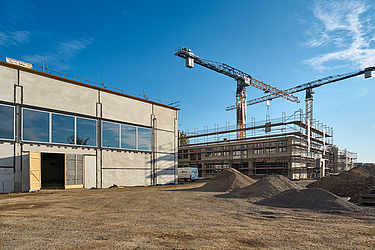 Rohbau mit Fenstern von außen; Gerüst an Gebäude und Kran im Hintergrund