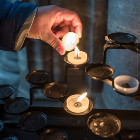 Hand, die ein Teelicht hält, das gerade entzündet wird