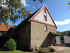 Haus mit braunem Putz und rotem Schiefer am Dach