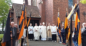 Viele Personen mit Weihbischof und Kolpingfahnen vor einer Kirche